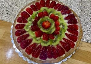 a fruit pizza with strawberries and kiwis on a table at Hotel Krial in Berat
