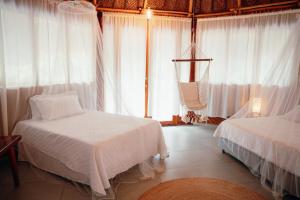 a bedroom with two beds and white curtains at Zirwa Hotel Boutique - Dentro del Parque Tayrona in El Zaino