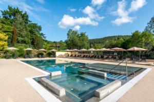 a swimming pool with chairs and umbrellas at Camping LA SERRE in Aigues-Vives