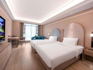 a hotel room with two beds and a flat screen tv at Mercure Chengdu Longtan in Chengdu