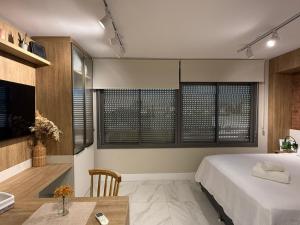 a bedroom with a bed and a table and a sink at Studio JP Redenção in Porto Alegre