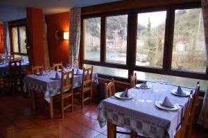 a dining room with tables and chairs and windows at Hotel Casa Julián in Peñamellera Alta