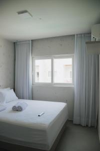 a bedroom with a white bed with a window at Curima Milagres in Passo de Camarajibe