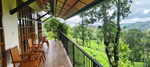 a balcony with wooden chairs and a view of the mountains at Serene Slopes in Vagamon