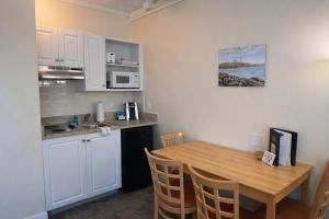 a kitchen with a wooden table and a kitchen with white cabinets at Courtyard Resort in Hyannis