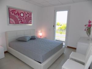 a white bedroom with a bed and a window at Hotel Residence Sole in Fontanafredda