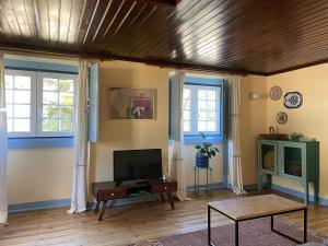 a living room with a flat screen tv and two windows at Casa Terra in Rio Maior