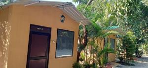 a small yellow building with a door and a porch at corbett motel in Rāmnagar