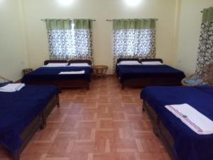 a room with three beds with blue sheets in it at corbett motel in Rāmnagar