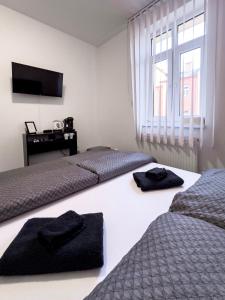 two beds in a room with a television and a desk at Hotel Central in Ostrava