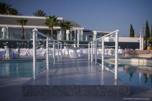 a bridge over a pool with white tables and chairs at Il Baglio Della Luna Relais by Le Dhome Sicily in Balestrate