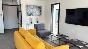 a living room with a yellow couch and a chair at Villa Lagune in Les Sables-d'Olonne