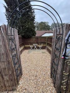an open gate in a fence with a table and chairs at Newly refurbished Annexe in Wareham