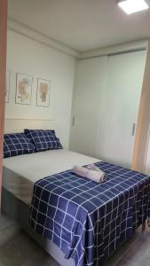 two beds in a room with a blue checkered blanket at Studio Aura in Barbacena