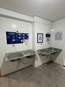 two sinks in a public bathroom with signs on the wall at Studio Aura in Barbacena