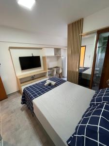 a bedroom with a large bed and a flat screen tv at Studio Aura in Barbacena