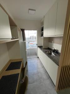 a small kitchen with white cabinets and a window at Studio Aura in Barbacena +11 photos