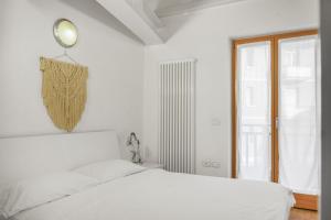 a white bedroom with a white bed and a window at Windshouse Apartments in Nago-Torbole