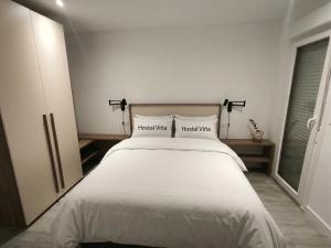 a bedroom with a white bed with two pillows at Hostal Viña in Outes