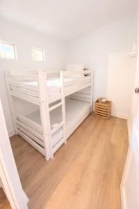 two white bunk beds in a room with a wooden floor at Les rives enchantées in Loches +5 photos