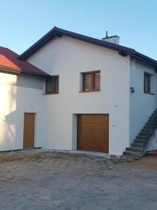 a white house with two garage doors and stairs at Mieszkanie Paszkówka in Paszkówka