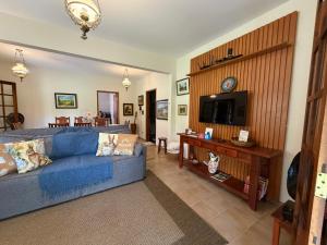 a living room with a blue couch and a tv at Sítio São Francisco da saudade Refugio Conforto e Afeto na Serra de Cunha a 200m do asfalto in Cunha