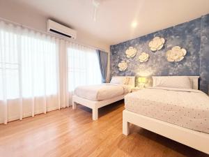a bedroom with two beds and a wall with flowers at THE MAISON Phuket in Ban Lo Long