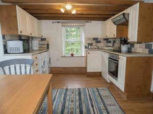 a kitchen with white cabinets and a large window at Cwm Ffernol in Machynlleth