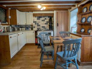 a kitchen with a wooden table and chairs at Cwm Ffernol in Machynlleth +4 photos
