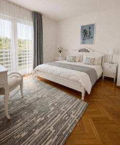a white bedroom with a bed and a large window at Bonita Apartments in Mostar