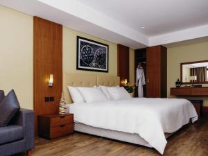 a bedroom with a large white bed and a chair at Mantis Kivu Marina Bay Hotel in Muhari