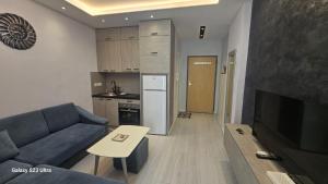 a living room with a blue couch and a kitchen at Arli's SeaFront Apartaments in Durrës