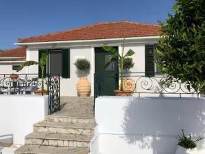 a white house with a green door and a porch at Lilac House Kefalonia in Ratzaklíon