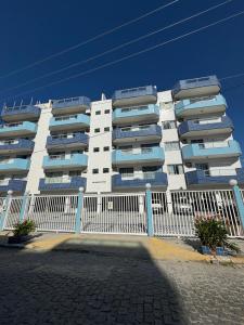 a white building with blue windows and a fence at Apartamento do Lala in Arraial do Cabo