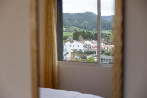 a bedroom window with a view of a town at Furnas Panorama House in Furnas