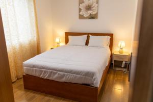 a bedroom with a bed with white sheets and two lamps at Furnas Panorama House in Furnas