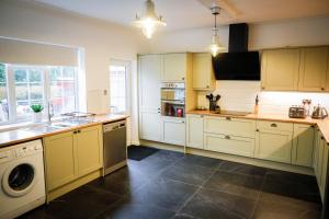 a kitchen with white cabinets and a washer and dryer at Spacious 4 Bed House Sleeps 8 in Quorn Near Loughborough in Quorndon