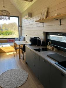 a kitchen with a counter and a table in a room at Lykke Huus Tinyhaus an der Nordsee mit Fasssauna in Schweiburg