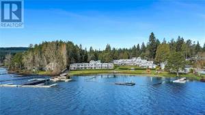 an aerial view of a large house on a lake at Lakefront Condo and Beach in Shawnigan Lake