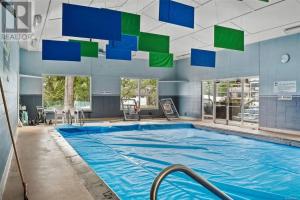 a large swimming pool with green and blue squares on the ceiling at Lakefront Condo and Beach in Shawnigan Lake