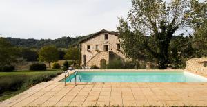 - une piscine en face d'une maison en pierre dans l'établissement CASALE SANTA CATERINA Jacuzzi and Pool, à Collazzone