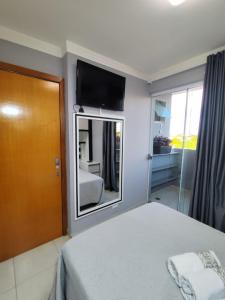 ein Schlafzimmer mit einem Bett und einem Fernseher an der Wand in der Unterkunft Apartamento em Maringá zona 07, próximo da universidade UEM in Maringá