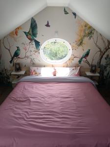 a bedroom with a large bed with a round window at Le clos des papillons in Carly