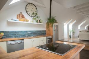 a kitchen with a sink and a clock on the wall at Courtyard Cottages in Tralee