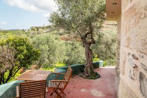 a patio with a table and chairs and a tree at Oliva Mare II in Agia Fotia