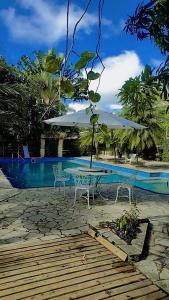 a table and chairs with an umbrella next to a pool at Ecos Jatobá - Refúgio à 12 km do Santuário de Aparecida in Guaratinguetá