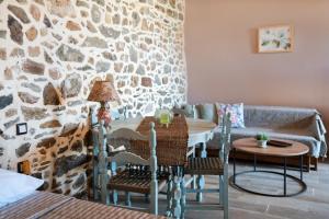 a room with a table and chairs and a stone wall at Oliva Mare II in Agia Fotia