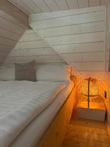 a bed in a wooden room with a lamp at Lykke Huus Tinyhaus an der Nordsee mit Fasssauna in Schweiburg