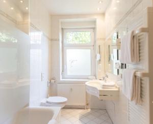 a bathroom with a toilet and a sink and a window at Hotel Markgraf Leipzig in Leipzig