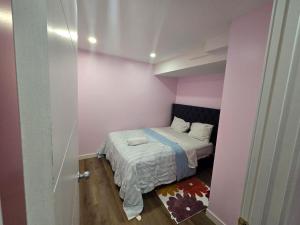 a small bedroom with a bed in a pink room at Bedroom in the basement Upland F in Edmonton